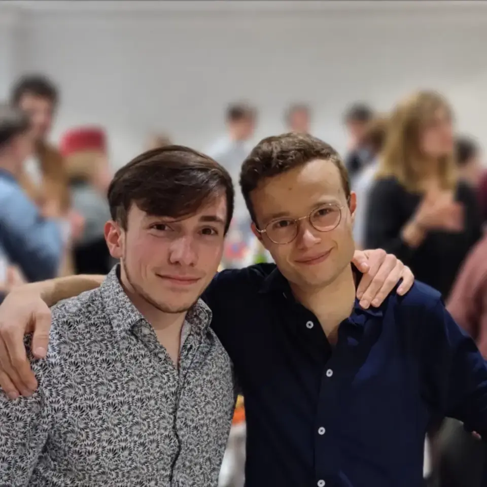 Thomas et un ami, souriants, le soir du lancement de sa start-up, au milieu des invités.